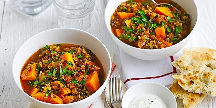 A bowl of lentil and sweet potato curry with a side of naan bread