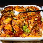 A baking dish of Korean Rice Cake Lasagna with melted, bubbly cheese on top.