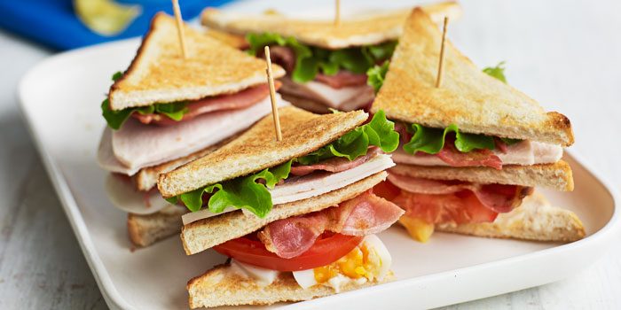 A classic club sandwich cut into quarters and held together with cocktail sticks.