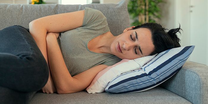 Woman experiencing abdominal discomfort in bed.