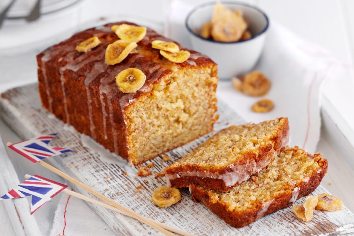 A classic banana bread loaf on a wooden board, cut into slices.