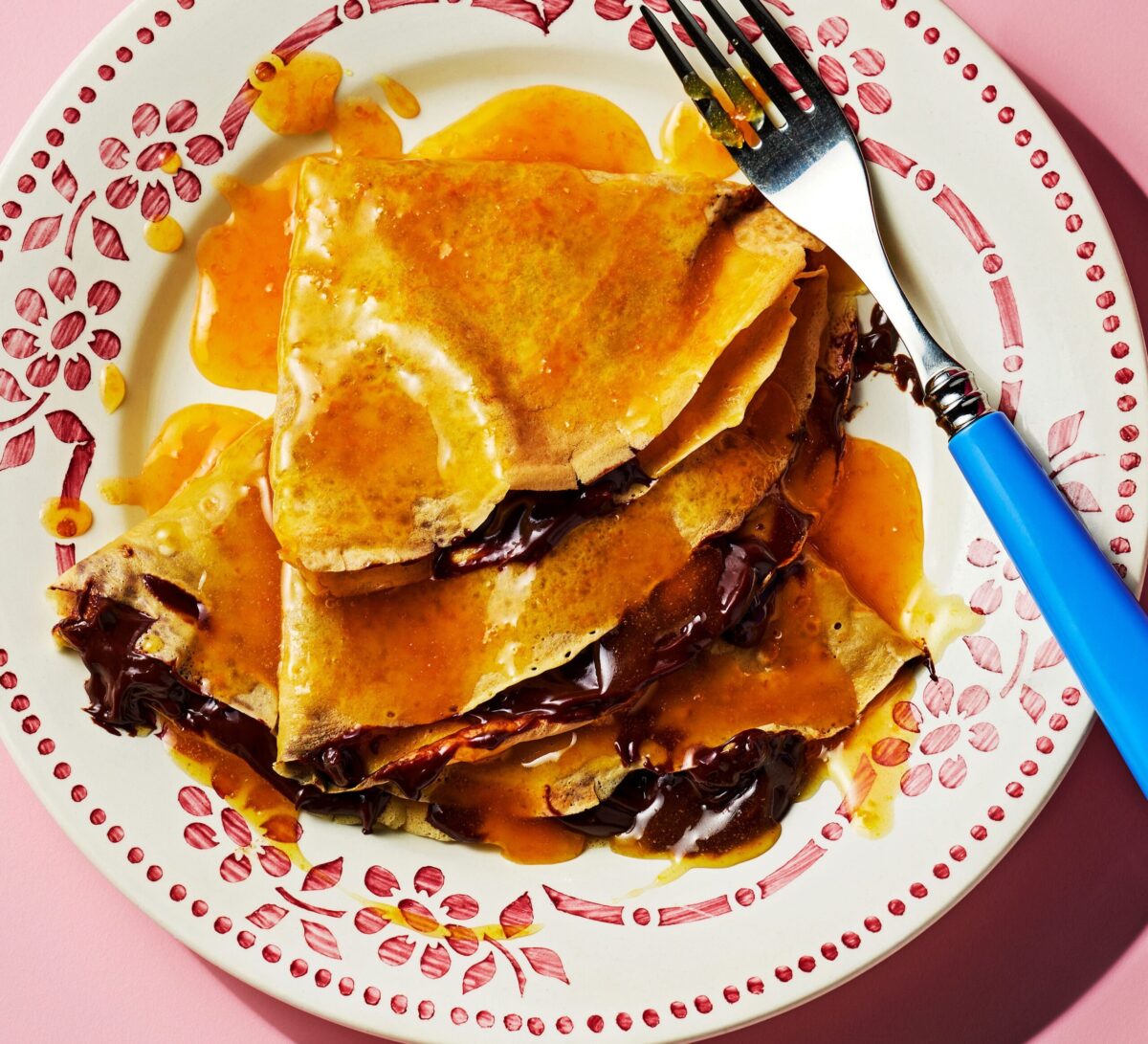 Folded chocolate crepes in an orange sauce.