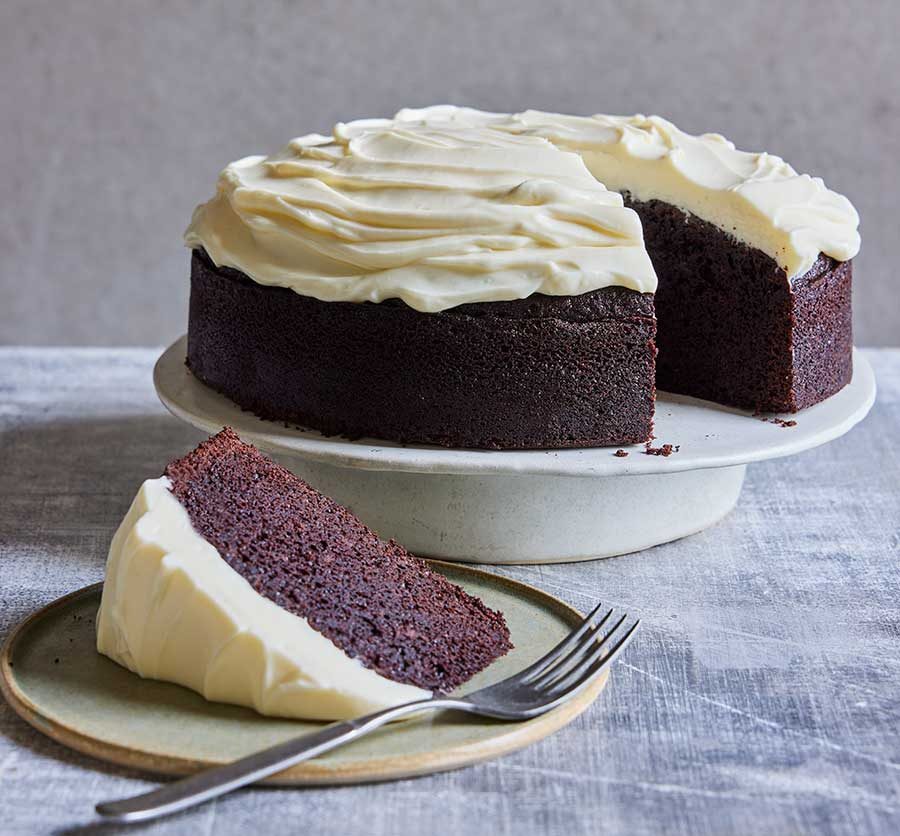 A whole Chocolate Guinness Cake on a cake stand, topped with creamy frosting.