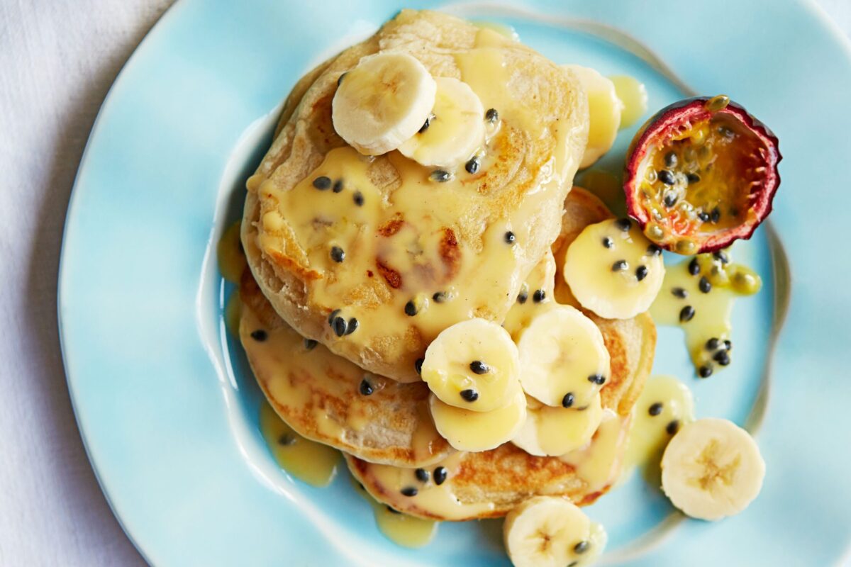 A stack of coconut banana pancakes with fruit