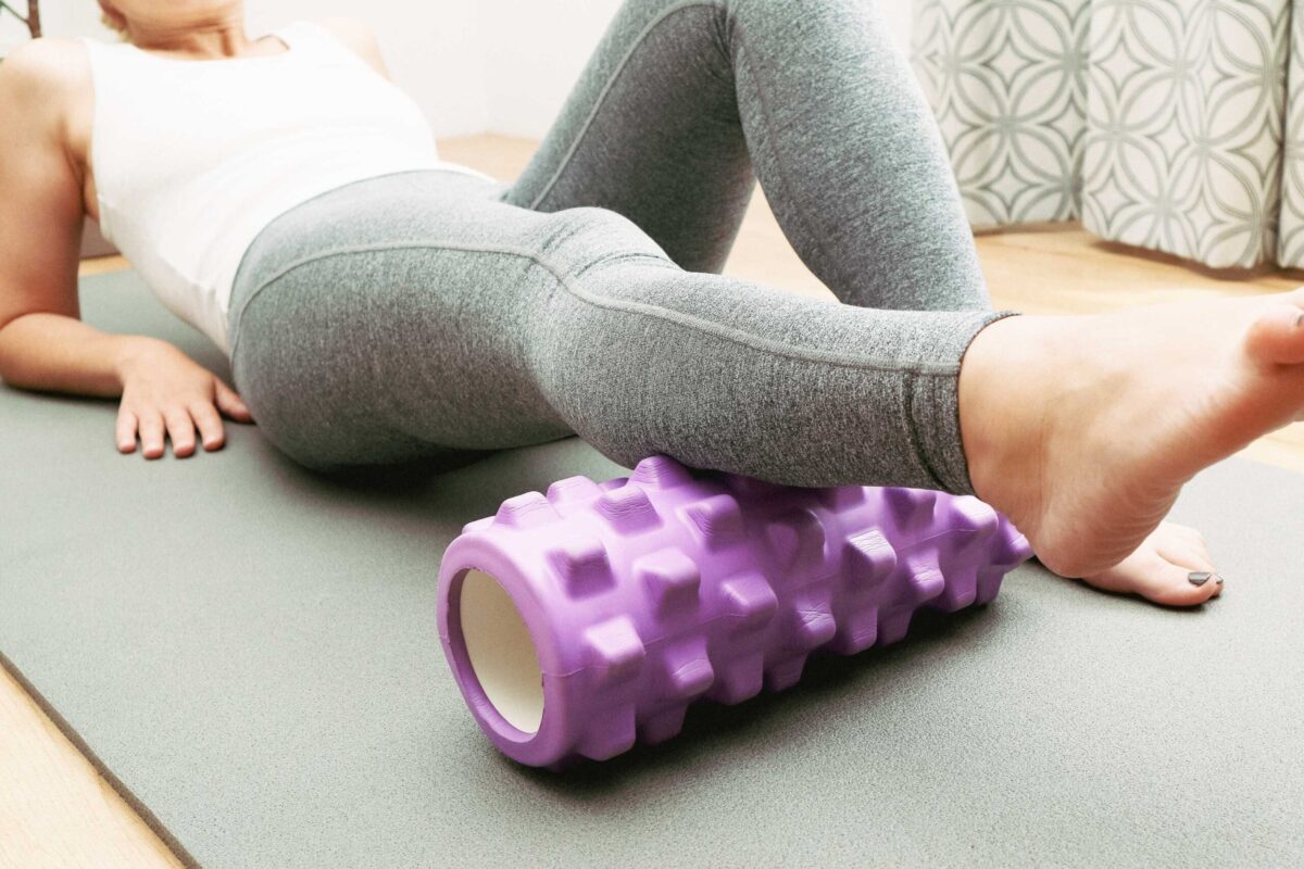 A woman using a foam roller on her leg muscle to relieve tension
