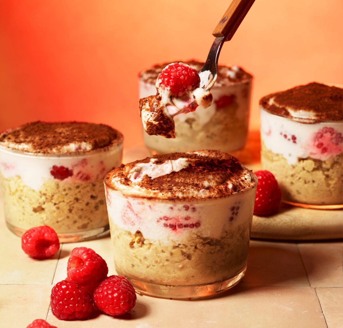 Tiramisu-style overnight oats and chia pudding in a glass, layered with raspberries and a dusting of cocoa.