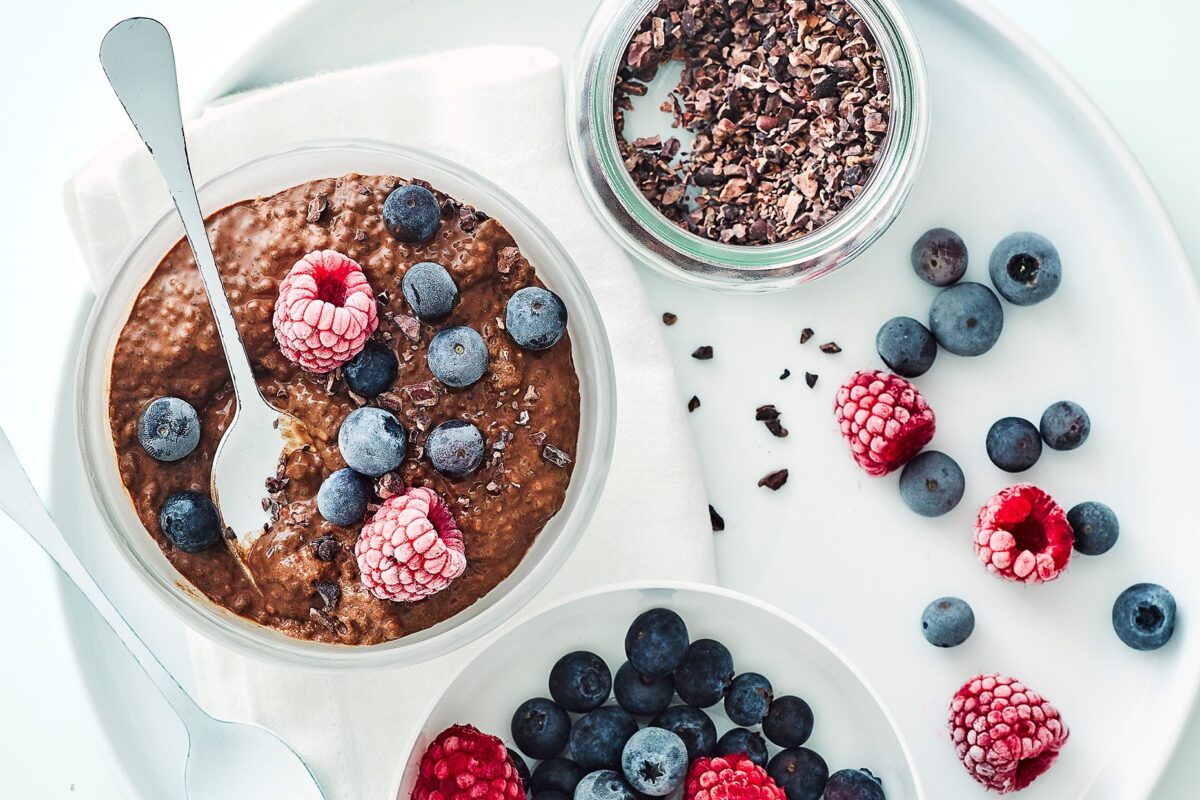 Rich chocolate chia pudding served in a glass with fresh raspberries and grated chocolate on top.