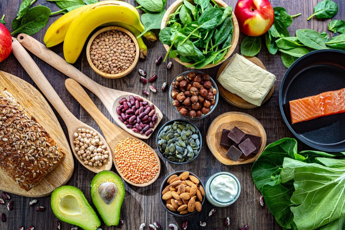 A beautiful flat lay of magnesium-rich foods including nuts, seeds, avocado, and dark leafy greens.
