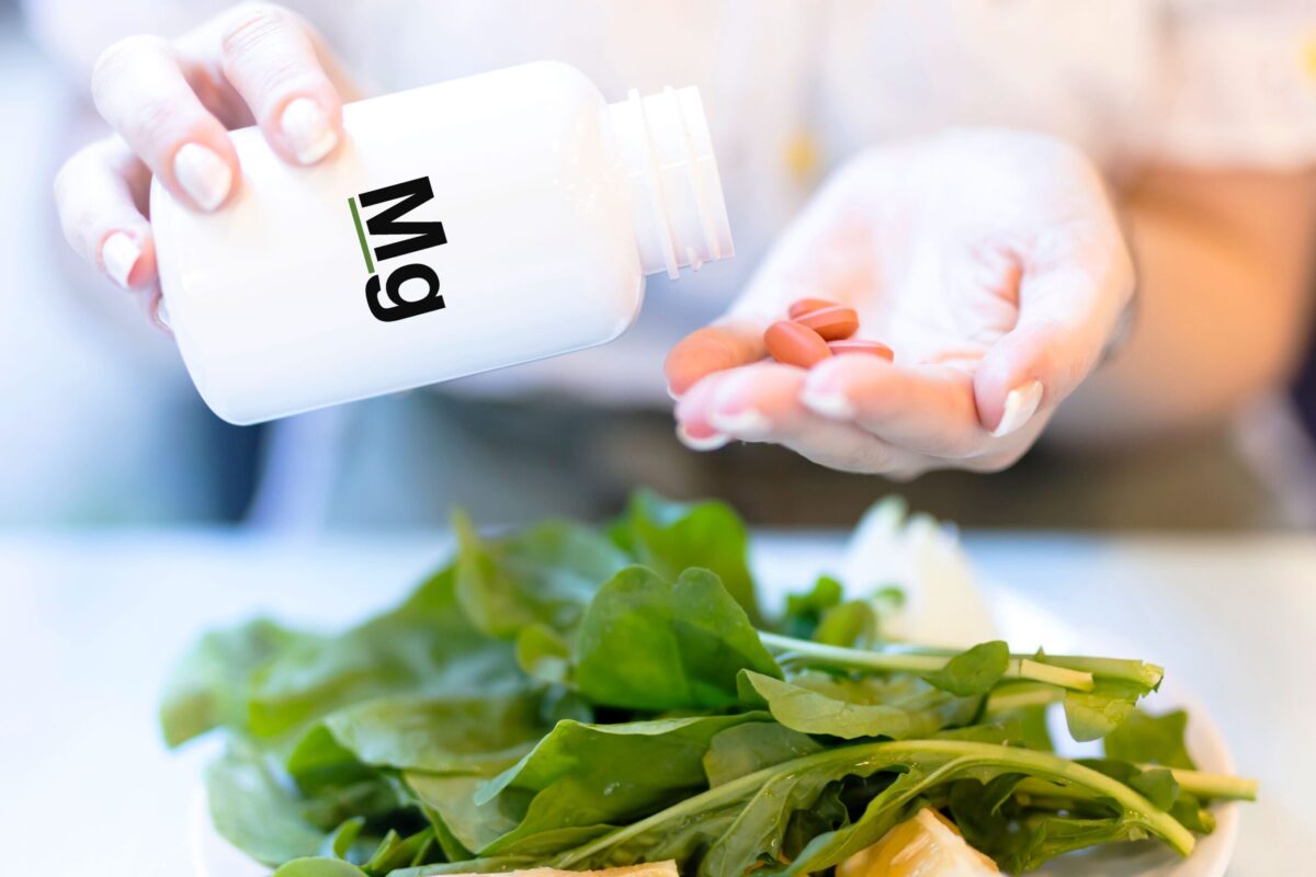 A bottle of magnesium supplements next to a glass of water.