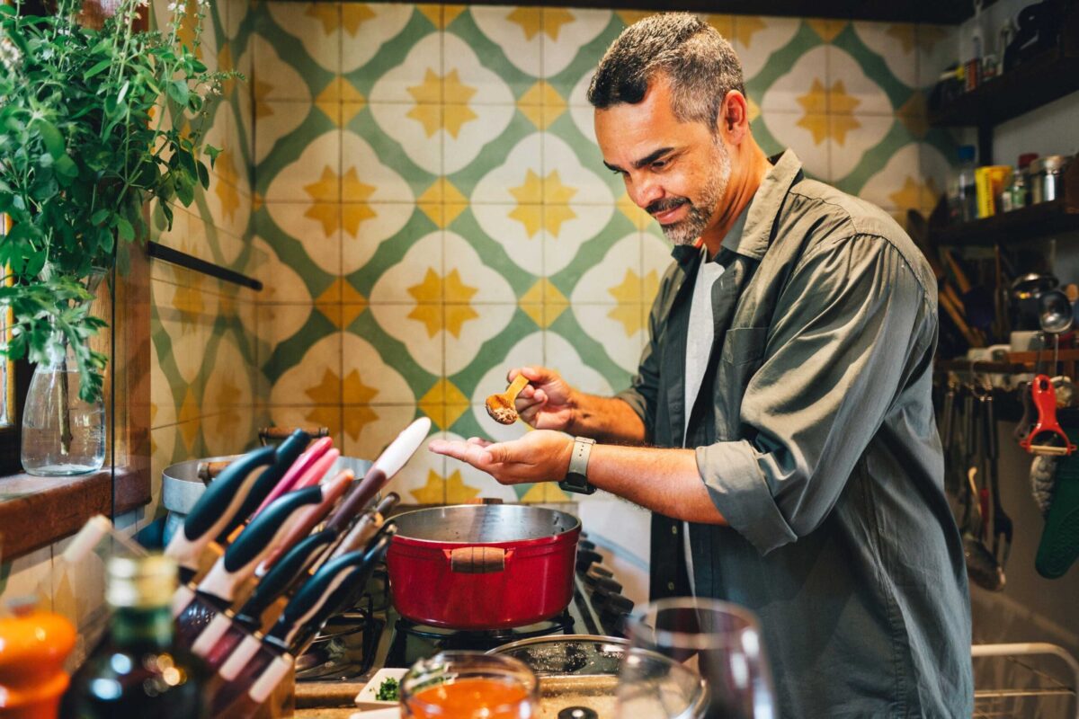 A man happily cooking a healthy meal in his kitchen.