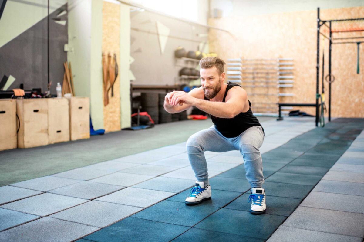 A man performing a bodyweight squat in a home gym setting