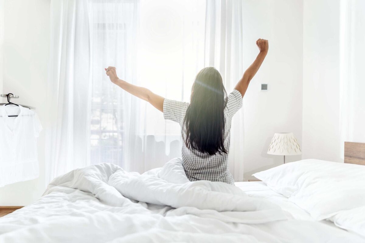 A woman waking up in the morning feeling refreshed and happy.