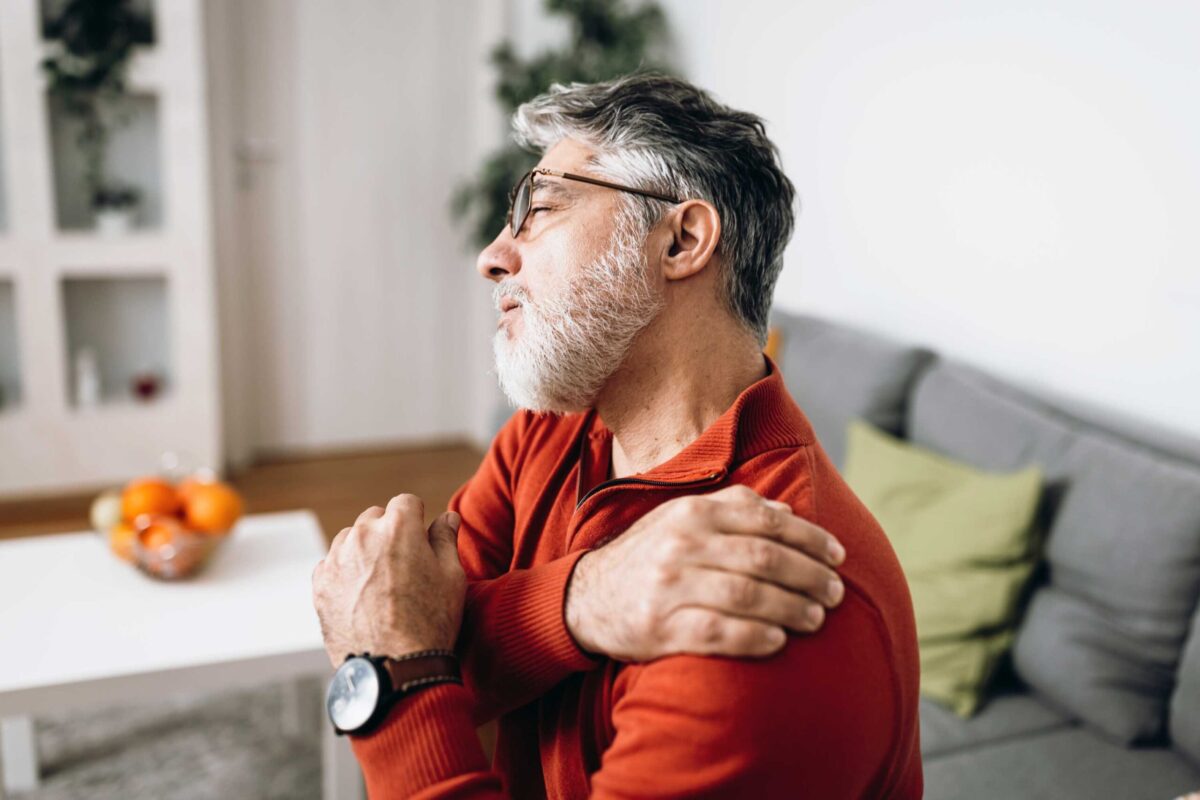 A person holding their shoulder in discomfort from a muscle knot