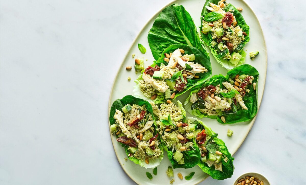 A vibrant pesto chicken salad with couscous in a bowl.