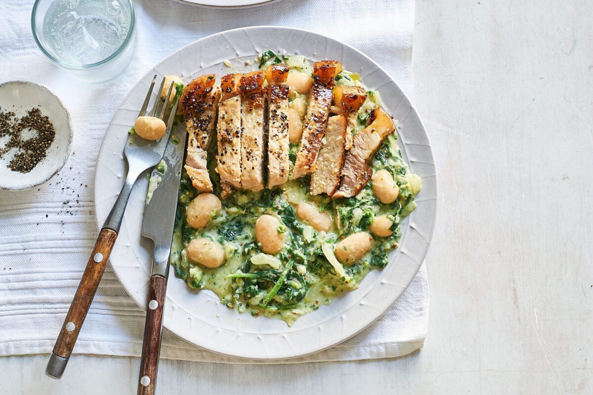 Plate of sliced pork chops with mustard butter beans and spinach