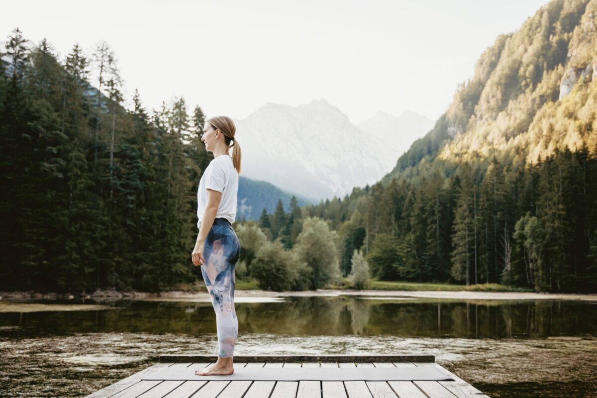 A person standing with good posture overlooking a calm lake.