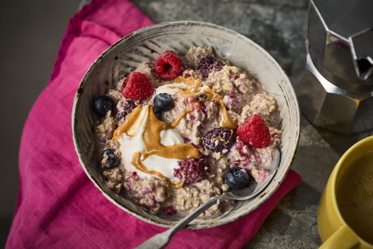 A bowl of protein-boosted overnight oats and chia, topped with yogurt, berries, and a drizzle of syrup.