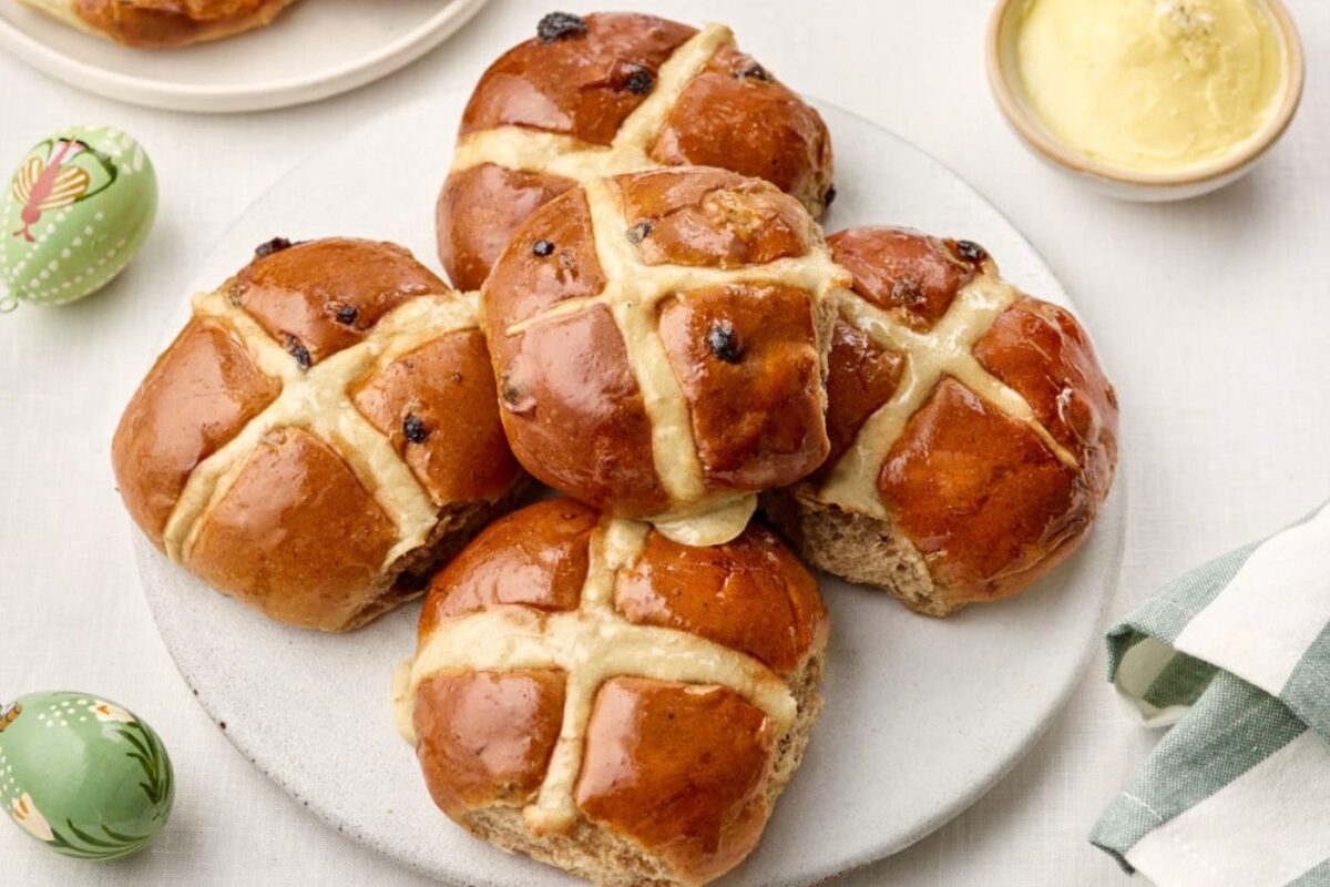 Artisanal hot cross buns piled on a plate.
