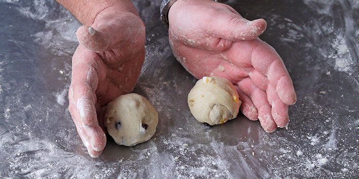 Shaped hot cross bun dough balls resting on a tray before the second rise.