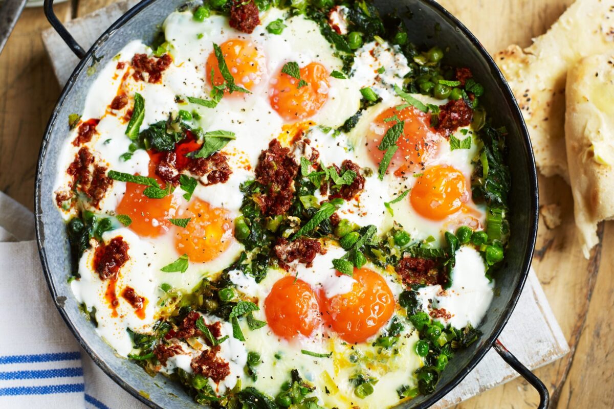 Green shakshuka with baked eggs in a pan