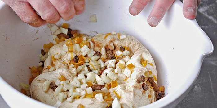 Adding mixed fruit and spices to the dough.