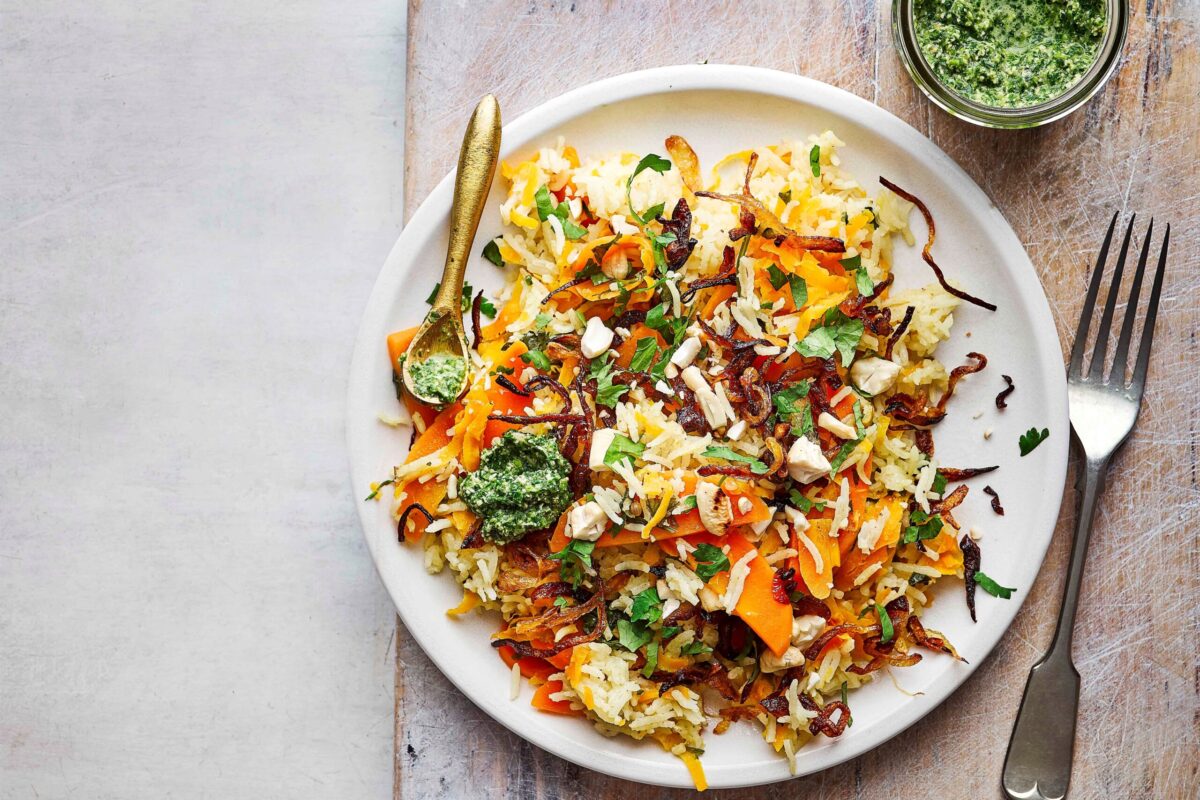 A close-up of delicious, vibrant carrot pilaf in a pan.