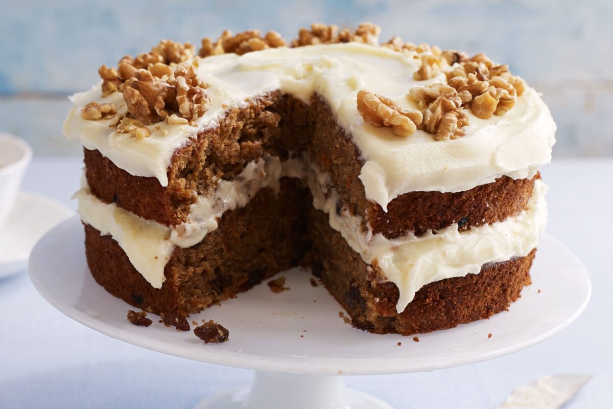 A slice of classic carrot cake with white cream cheese frosting on a plate.