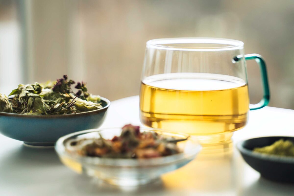 A cup of green tea being poured from a teapot
