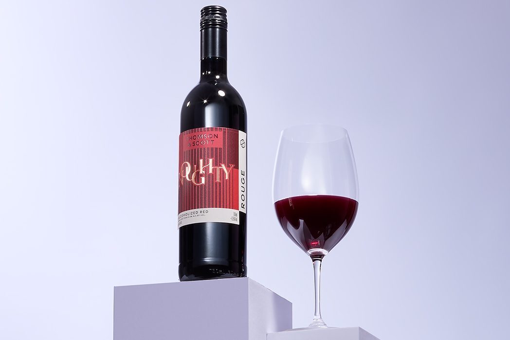 A glass and bottle of red non-alcoholic wine.