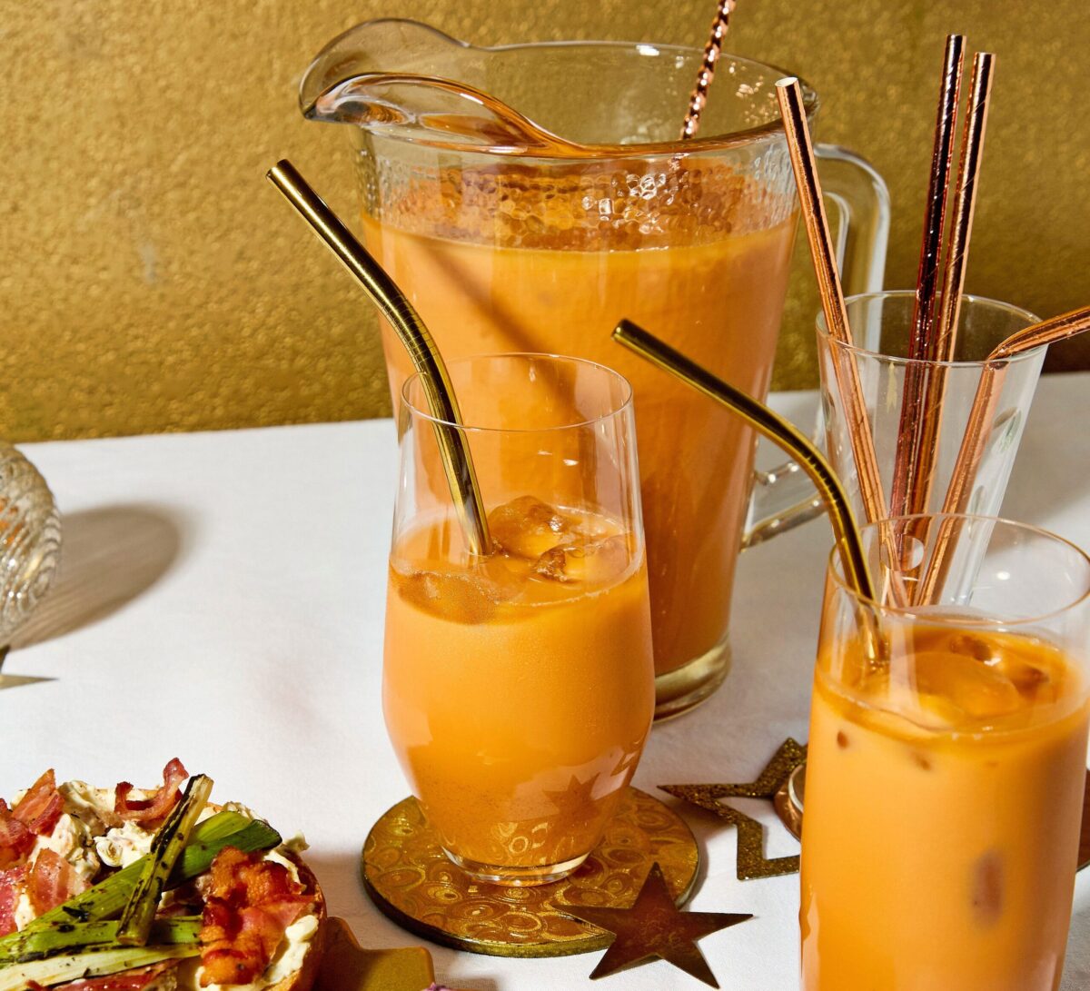 A large pitcher and glasses filled with vibrant orange Thai iced tea.