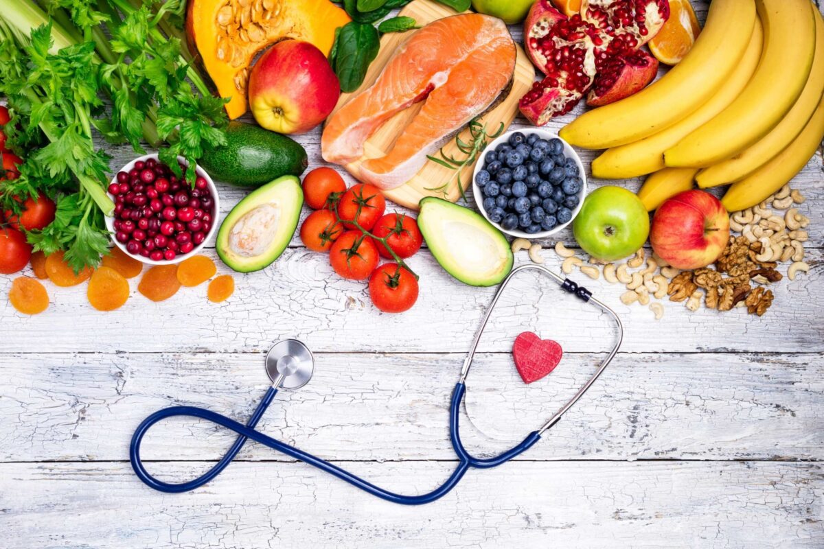 A stethoscope resting on heart-healthy foods like avocado and nuts.
